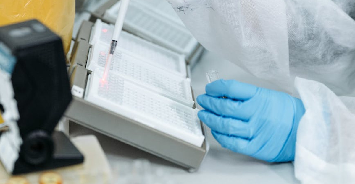 Professional in protective gear using a pipette in a laboratory setting with advanced equipment