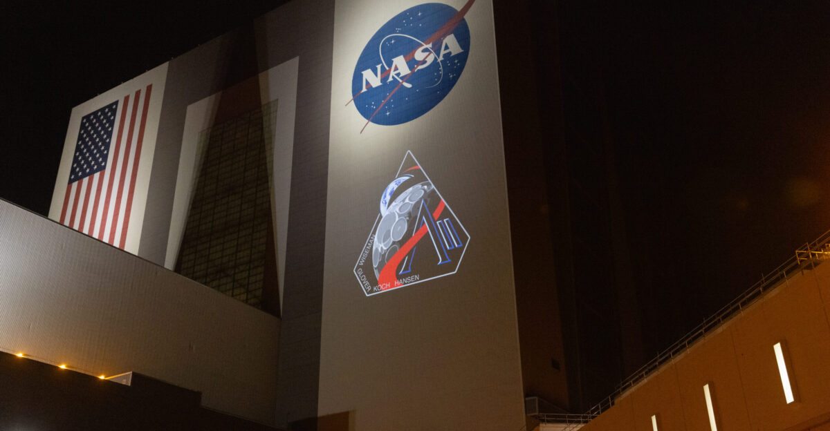 The official Artemis II mission crew insignia is projected on the exterior of the Vehicle Assembly Building at NASA s Kennedy Space Center in Florida on Friday April 4 2025 The patch designates the mission as AII signifying not only the second major flight of the Artemis campaign but also an endeavor of discovery that seeks to explore for all and by all Framed in Apollo 8 s famous Earthrise photo the scene of the Earth and the Moon represents the dual nature of human spaceflight both equally compelling The Moon represents our exploration destination focused on discovery of the unknown The Earth represents home focused on the perspective we gain when we look back at our shared planet and learn what it is to be uniquely human The orbit around Earth highlights the ongoing exploration missions that have enabled Artemis to set sights on a long-term presence on the Moon and soon Mars