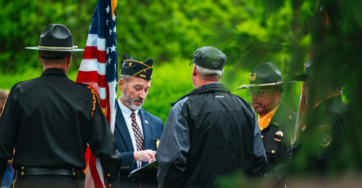 Uniformed individuals gather with USA flag engaging in official outdoor ceremony