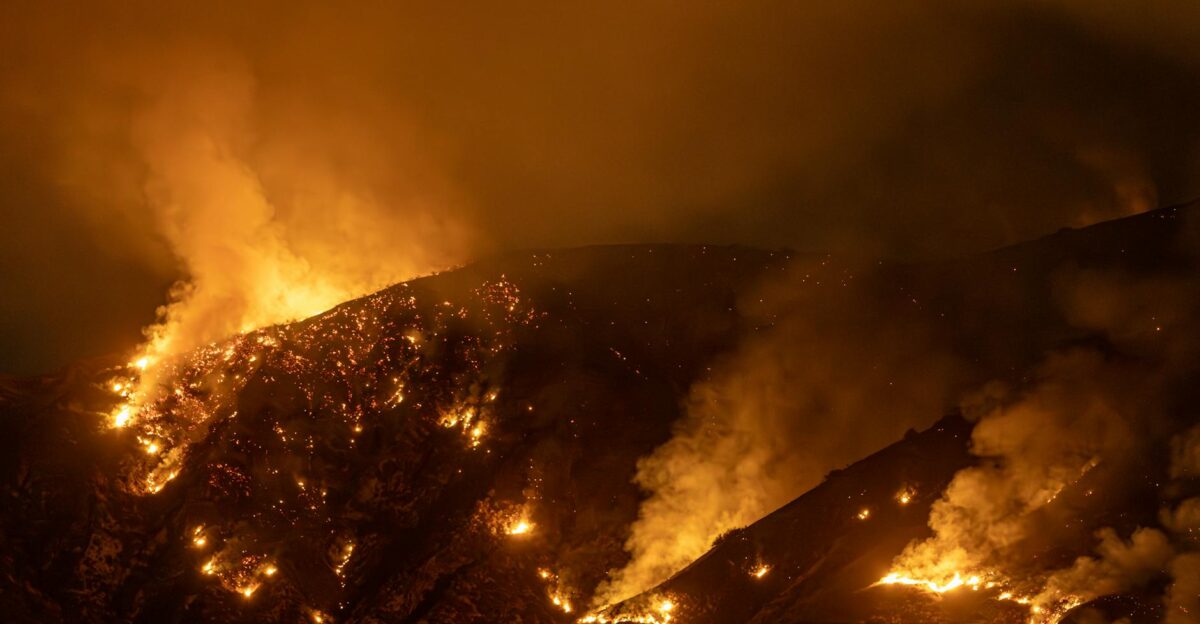 Intense wildfire blazing through mountains in California at night creating a dramatic scene