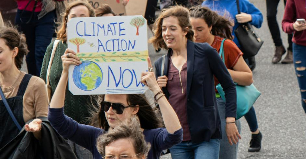 A vibrant climate march with diverse group holding signs demanding climate action