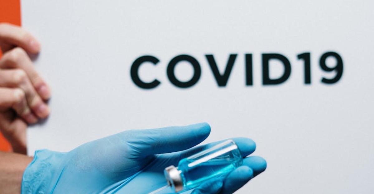 Healthcare worker with syringe and vaccine highlighted by COVID-19 sign