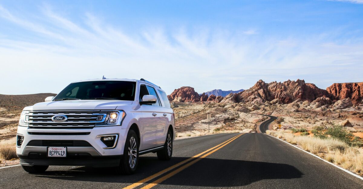 a white suv driving down a desert road