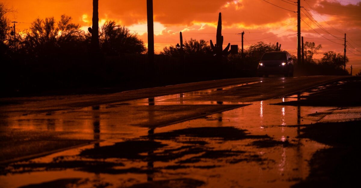 a wet street with a car driving down it